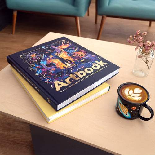 Two art books stacked on a table with the solar system enamel mug.